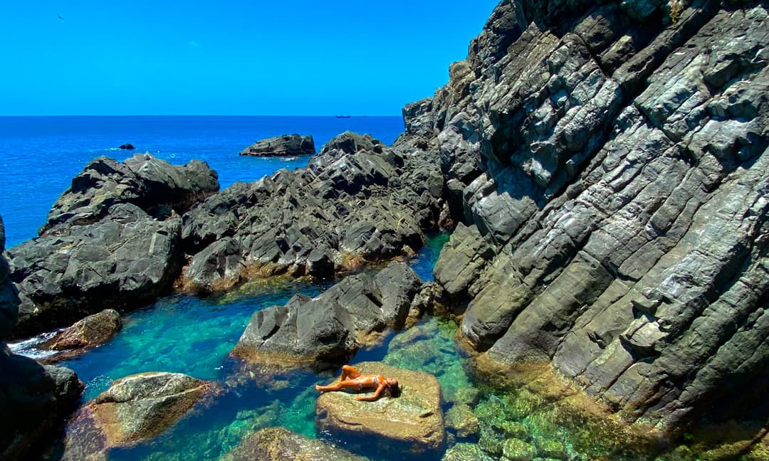 Mulher deitada em piscina natural entre rochas vulcânicas em Fernando de Noronha
