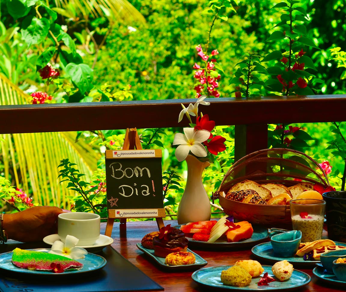 Mesa de desayuno abundante servido en el balcón de Pousada Do Vale, rodeado por el Jardim Elizabeth